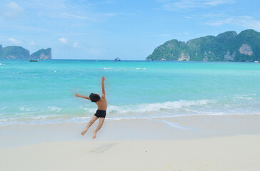 Fototapeta na wymiar Little boy jumping in front of Koh Phi Phi Island beach in Thailand