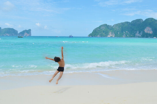 Little boy jumping in front of Koh Phi Phi Island beach in Thailand