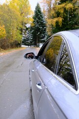 Fototapeta na wymiar Autumn travel and trips.Road view.First snow. Travel by car. Car on the autumn road.Silver color car on the road with autumn trees and the first snow. Late fall season.