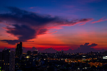 Obraz premium The high angle background of the city view with the secret light of the evening, blurring of night lights, showing the distribution of condominiums, dense homes in the capital community