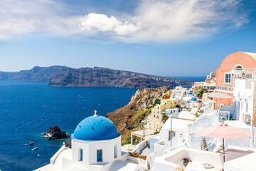 scenic view at greek Mediterranean island Santorini with beautiful white buildings , deep blue sea, rocks and blue cloudy sky on a background