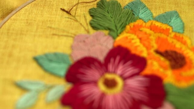 Beautiful embroidery flowers on cotton fabric. Product of needlework on a piece of embroidery. Needlework is decorative sewing and textile arts handicrafts. How to stitch embroider flowers on clothes.