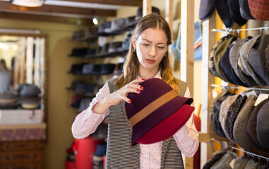 Young female shopper looking for hat in showroom