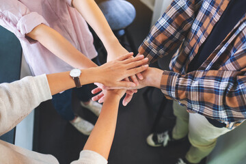 Closeup image of business team standing and joining their hands together in office
