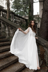 Fototapeta premium Wedding in an old villa in European style, trends 2021. The bride walks up the stairs of the villa overlooking the garden.