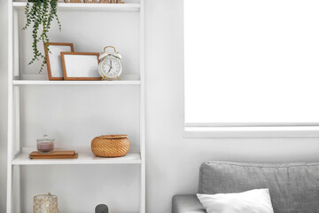 Modern shelf with alarm clock and decor near white wall