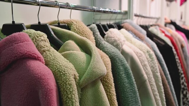 Faux fur coats. Women's winter fur coats hang in a row on hangers