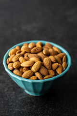 Almond nuts in bowl on black table.
