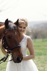 Obraz premium An attractive bride next to a horse. Wedding photography with a horse at sunset.