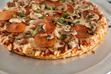 A closeup view of the toppings of a dairy-free and gluten-free frozen pizza, resting on a stove top.