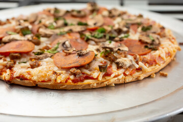 A view of the toppings of a dairy-free and gluten-free freshly oven baked pizza, resting on a stove top.