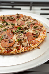 A view of the toppings of a dairy-free and gluten-free freshly oven baked pizza, resting on a stove top.