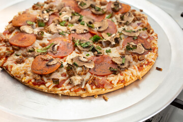 A view of the toppings of a dairy-free and gluten-free freshly oven baked pizza, resting on a stove top.