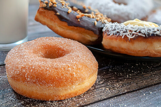 close up an image or macro photography of donuts on a rustic table with sugar spread and a glass of milk on the side