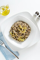 vegan risotto with black lentils and artichokes in a white plate on the table