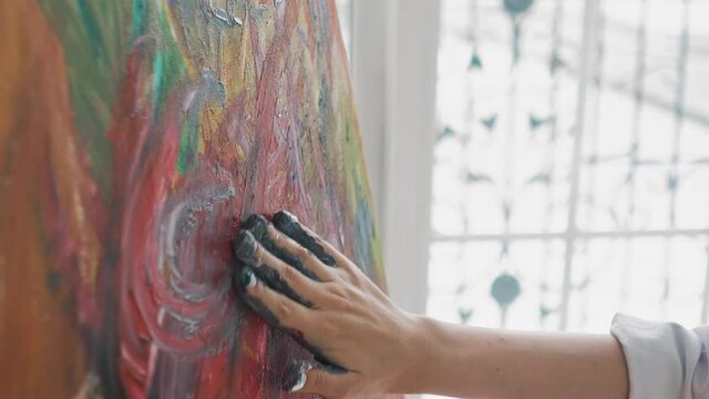 Talented woman at work on abstract painting making strokes