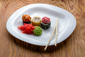 sushi rolls wasabi ginger and chopsticks on a plate on the table