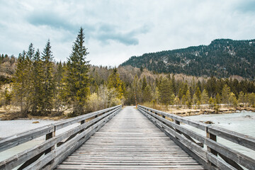 Fototapeta na wymiar Einsame Holzbrücke in den Alpen über einen Fluss