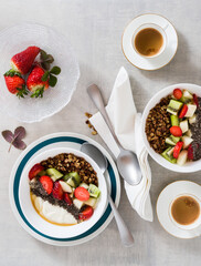 breakfast with granola, yogurt, fresh fruit, chia seeds, maple syrup and berries in plates on the table