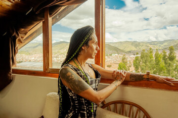 Mujer transgénero mirando la vista del paisaje a través de su ventana 