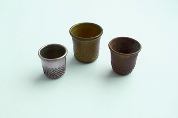 Three vintage thimbles stand in a row isolated on a colored background. 