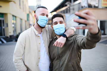 Fototapeta na wymiar Men friends outdoors on street in town taking selfie, coronavirus and new normal concept.