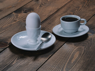 A cup of freshly brewed aromatic coffee and an egg on a stand