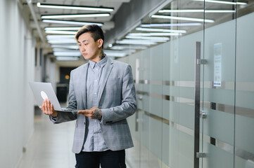 Fototapeta premium Happy young man sitting in modern office and looking at the camera with smile