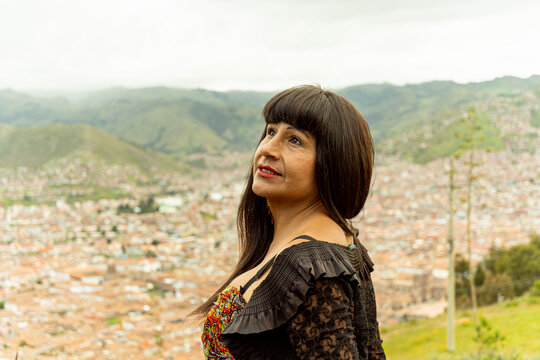 Mujer transg&eacute;nero observando el cielo con vista a la ciudad de Cusco 