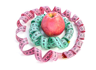 Bright colored measuring tapes, twisted in a spiral, in the center of a red apple, isolated on a white background. Healthy and proper nutrition, calorie content. Fitness, diet, weight loss concept.
