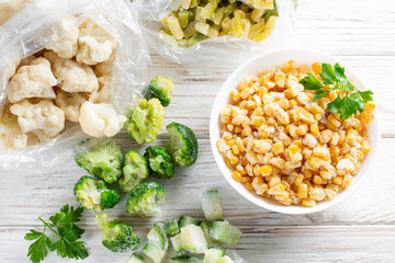 Frozen mixed vegetables in a bag on white wooden table. Frozen food. Top view