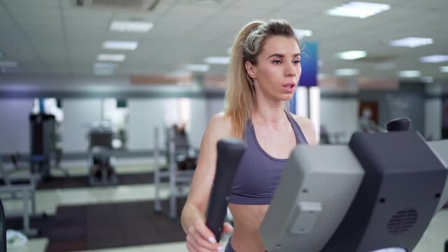 Young woman working out on orbi track at gym exercising