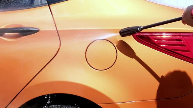 Manual car wash with pressurized water in car wash outside in summer.