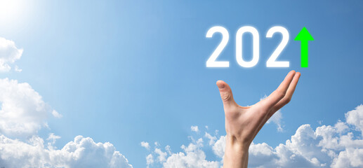 Hand hold 2021 positive icon on sky background.Plan business positive growth in year 2021 concept. Businessman plan and increase of positive indicators in his business, Growing up business concepts.