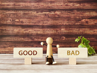 茶色の板壁の前の木の人形と2枚のプレート_Good bad文字入り