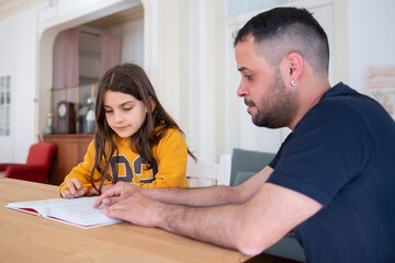 Bewildered father helping his daughter with difficult homework. Focused Caucasian girl and dad sitting at table, preparing for lesson. Education, parenthood concept