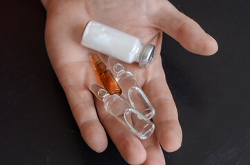 A hand, three ampoules, and a bottle of white powder.