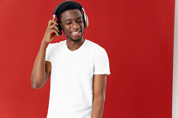 smiling man in white t-shirt wearing headphones music lover red background