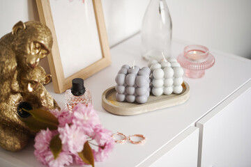 A grey-blue bubble candle on a white surface surrounded by pink cherry blossom
