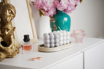 A grey-blue bubble candle on a white surface surrounded by pink cherry blossom