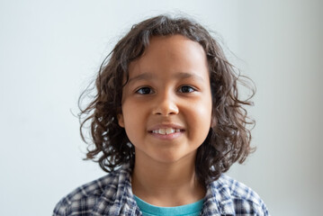 Close-up of curly-haired smiling boy. Isolated portrait of Caucasian kid looking at camera on white background. Happy boy concept