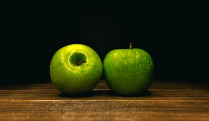 two green apple on a wooden board on a black background