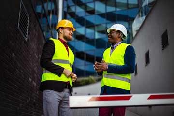 Engineer discussing the structure of the building with architects colleague at construction site. Businessmen talking.