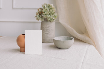 Collection of styled homeware objects, white blank paper mock up, linen curtain. Modern home decor. Copy space.