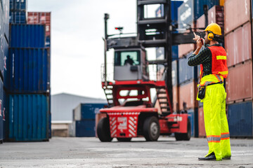 Professional engineer container cargo foreman in helmets working standing and using walkie talkie checking stock into container for loading.logistic and business export