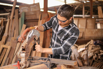 Young Caucasian carpenter man is fixking the sawing machine in his own garage style workshop for hobby