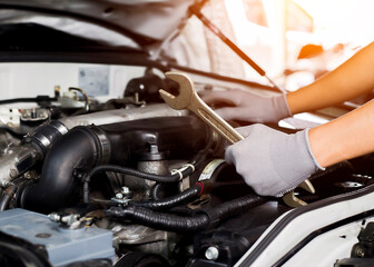 Car mechanic working on car engine, car maintenance concept.
