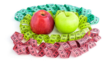 Bright colored measuring tapes, twisted in a spiral around a red and green apple, isolated on a white background. Fitness, diet, weight loss concept. Weight loss.