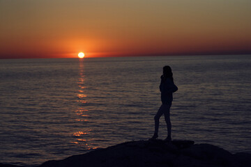 Fototapeta premium silhouette of a woman by the sea in the mountains in nature