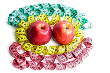 Two red apples and a centimeter tape isolated on a white background. Colored measuring tapes, twisted in a spiral around apples. Healthy and proper nutrition,calorie content.Diet, weight loss concept.